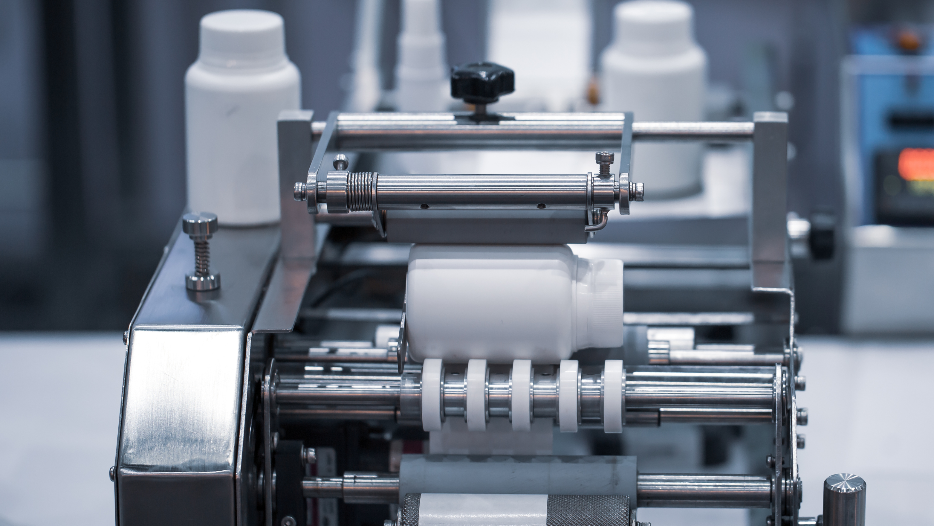 plastic container being labelled in a label applicator machine