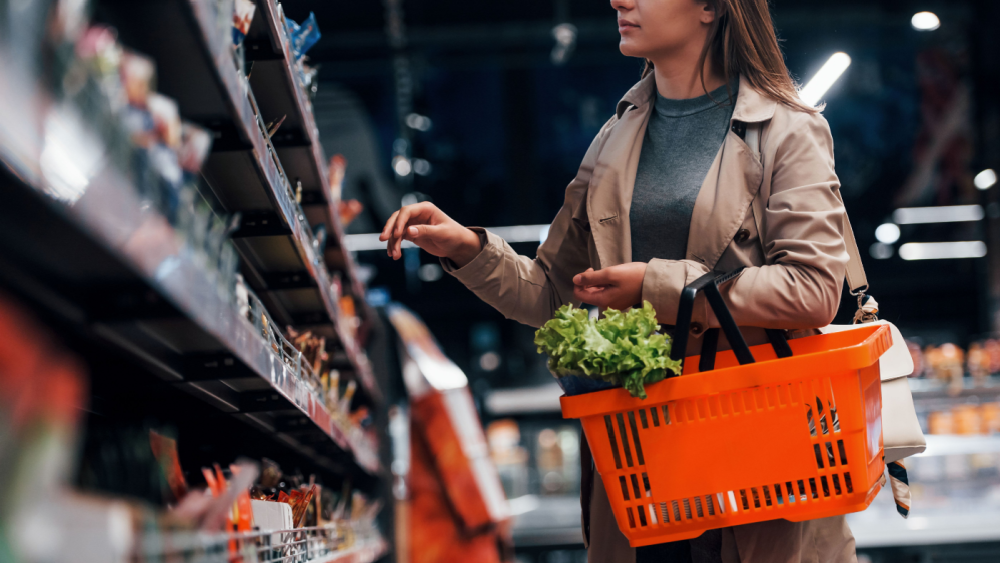 Woman standing in front of a store shelf with a basket in her arm